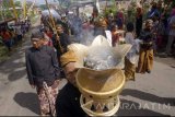 Warga dan anak-anak berpakaian adat mengarak aneka sesajen berbentuk kembang dan hasil bumi dalam rangkaian tradisi ulur-ulur di Telaga Buret, Tulungagung, Jawa Timur, Jumat (4/8). Tradisi ulur-ulur dengan melakukan ritual jamasan sepasang arca dewa perlambang kemakmuran dan kesuburan itu digelar setiap tahun dengan dasar penanggalan Jawa, sebagai wujud ungkapan rasa syukur petani kapada Tuhan atas limpahan air Telaga Buret yang menjadi sumber pengairan bagi pertanian sekitarnya. Antara Jatim/Destyan Sujarwoko/zk/17