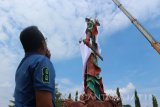 Petugas Badan Penanggulangan Bencana Daerah (BPBD) Pemkab Tuban, Jawa Timur, dengan alat berat 'crane' menutup patung Dewa Perang Kong Co asal Tiongkok dengan kain putih di Kelenteng Kwan Swie Bio, Minggu (6/8). Patung setinggi 30,4 meter itu ditutup dengan kain karena permintaan pengurus kelenteng untuk meredam konflik dengan sejumlah elemen masyarakat yang menolak bangunan patung itu.Antara Jatim/Slamet Agus Sudarmojo/zk/17