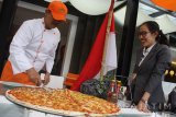 Seorang koki memotong pizza raksasa untuk dibagikan pada pengunjung di Hotel Harris, Malang, Jawa Timur, Senin (14/7). Menu pizza berdiameter 75 centimeter tersebut sengaja dibuat untuk menyambut HUT Kemerdekaan RI sekaligus menarik minat pengunjung. Antara Jatim/Ari Bowo Sucipto/zk/17.