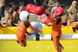 Sejumlah pelajar mengikuti lomba 'Gebuk Bantal' di atas kolam buatan di halaman SD Muhammadiyah 4 Pucang Surabaya, Jawa Timur, Rabu (16/8). Berbagai kegiatan lomba yang bersifat menghibur digelar berbagai kalangan masyarakat untuk menyemarakkan HUT Ke-72 RI. Antara Jatim/Didik Suhartono/zk/17