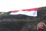 Semen Padang Bentangkan Bendera Raksasa di Puncak Bukit Karang Putih