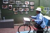 Penjaja makanan melihat foto yang dipajang di pinggir jalan dalam Pameran Foto bertajuk 'Lebur' di Malang, Jawa Timur, Selasa (22/8). Pameran yang berlangsung selama empat hari tersebut menampilkan delapan foto story dari para fotografer muda sebagai upaya mendekatkan seni fotografi pada masyarakat. Antara jatim/Ari Bowo Sucipto/zk/17.