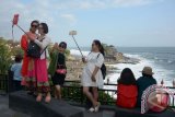 Wisatawan melakukan panggilan video dan berfoto saat libur Idul Adha dengan latar Objek Wisata Tanah Lot, Tabanan, Bali, Sabtu (1/9). Telkomsel telah memperkuat sekitar 1.500 Base Transceiver Station (BTS) di area sekitar lokasi wisata untuk menunjang fasilitas pelayanan terhadap wisatawan karena tingginya penggunaan layanan data antara lain dipicu seringnya wisatawan mengunggah foto dan video aktivitas serta panorama ke media sosial maupun mengirim pesan melalui layanan data. Antara Bali/Gede Wira Suryantala/nym/17. 