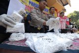 Polisi menunjukkan tersangka dan barang bukti saat ungkap kasus peredaran pil 'Double L' di Polsek Asemrowo, Surabaya, Jawa Timur, Jumat (22/9). Polsek Asemrowo menangkap tiga tersangka berinisial  D N (39). A M S (39) dan M I (31) atas kasus dugaan mengedarkan pil 'Double L' yang secara umum diedarkan di kalangan remaja dan polisi mengamankan barang bukti pil 'Double L' sebanyak 92.800 butir, dua telepon genggam dan sejumlah uang tunai. Antara Jatim/Didik Suhartono/mas/17