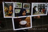 Pengunjung melihat foto yang dipajang dalam Pameran Foto bertajuk 'Setjangkir Tjerita Kopi' di Malang, Jawa Timur, Senin (25/9). Pameran yang berlangsung selama seminggu tersebut menampilkan foto cerita dari fotografer muda tentang kerja keras petani kopi hingga bisnis gerai kopi. Antara Jatim/Ari Bowo Sucipto/uma/17.