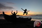 Warga bermain lompatan saat matahari terbenam (sunset) di Pantai Wisata Kampung Jawa, Banda Aceh, Rabu (27/9/2017). Lokasi tersebut menjadi salah satu destinasi favorit wisatawan di kawasan itu. (ANTARA FOTO/Ampelsa)