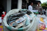 Personel kepolisian berjaga di dekat barang bukti surat izin mengemudi (SIM) yang telah habis masa berlaku untuk diubah datanya, saat gelar kasus pembuatan SIM palsu, di Medan, Sumatera Utara, Sabtu (30/9). Pihak Polda Sumut berhasil menangkap tiga orang tersangka pembuatan SIM palsu, dengan barang bukti jutaan lembar SIM yang telah habis masa berlaku, 33 lembar siap edar dan 46 lembar telah diedarkan. Satu tersangka diantaranya merupakan anggota kepolisian. ANTARA FOTO/Irsan Mulyadi/wdy/2017.