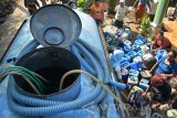 Sejumlah warga antre untuk mendapatkan air bersih yang disalurkan dari truk tangki di Winongan, Pasuruan, Jawa Timur, Sabtu (30/9). Bantuan air bersih yang disalurkan Badan Penanggulangan Bencana Daerah (BPBD) bekerjasama dengan Pemerintah Daerah setempat tersebut untuk membantu warga yang kesulitan mendapatkan air bersih akibat musim kemarau. Antara Jatim/Umarul Faruq/mas/17.