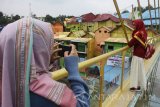 Wisatawan melakukan berfoto di atas jembatan kaca yang baru diresmikan penggunaannya di Jodipan, Malang, Jawa Timur, Selasa (10/10). Jembatan kaca yang desainnya meniru jembatan kaca di Zhangjiajie-China tersebut sengaja dibangun untuk menghubungkan dua kampung tematik yakni kampung warna-warni Jodipan dan kampung 3D-Ksatrian Malang sebagai upaya menarik wisatawan untuk berkunjung. Antara Jatim/Ari Bowo Sucipto/mas/17.