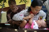 Kader posyandu menimbang anak balita di Posyandu Kenikir yang menggunakan ruangan dibawah tandon air di Kotalama, Malang, Jawa Timur, Rabu (11/10). Menurut survey yang dilakukan UNICEF, kurangnya infrastruktur posyandu yang memadai dan kesadaran masyarakat yang rendah menjadi hambatan utama bagi keberhasilan program imunisasi campak-rubela di Indonesia sehingga hanya mencapai angka 80-82 persen atau lebih rendah dari sejumlah negara di Asia seperti Thailand dan Maladewa. Antara Jatim/Ari Bowo Sucipto/uma/17.