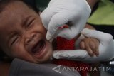 Kader posyandu memberikan imunisasi polio pada anak di Posyandu Kenikir yang menggunakan ruangan dibawah tandon air di di Kotalama, Malang, Jawa Timur, Rabu (11/10). Menurut survey yang dilakukan UNICEF, kurangnya infrastruktur posyandu yang memadai dan kesadaran masyarakat yang rendah menjadi hambatan utama bagi keberhasilan program imunisasi campak-rubela di Indonesia sehingga hanya mencapai angka 80-82 persen atau lebih rendah dari sejumlah negara di Asia seperti Thailand dan Maladewa.. Antara Jatim/Ari Bowo Sucipto/uma/17.