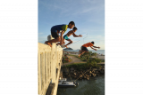 Sejumlah anak meloncat dari jembatan Purus, Padang, Sumatera Barat, Kamis (12/10). Atraksi anak-anak pantai tersebut menjadi daya tarik bagi pengunjung pantai Padang yang terkadang memberikan saweran (uang) kepada mereka. ANTARA FOTO/Iggoy el Fitra/pd/17