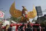 Warga menggotong lambang Garuda Pancasila saat mengikuti pawai Sedekah Bumi di Wiyung, Surabaya, Jawa Timur, Minggu (22/10). Sedekah Bumi tersebut merupakan wujud syukur kepada Tuhan atas rezeki dan hasil panen yang melimpah. Antara Jatim/Moch Asim/17.