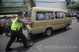 Polisi mendorong angkutan kota (angkot) yang menutupi jalan ketika berunjuk rasa di jalan Gubernur Suryo, Surabaya, Jawa Timur, Selasa (31/10). Dalam aksi unjuk rasa tersebut para sopir angkot menuntut agar Gubernur Jawa Timur segera menerbitkan Peraturan Gubernur (Pergub) untuk membatasi beroperasinya angkutan berbasis aplikasi online yang dinilai menurunkan pendaptan mereka. Antara Jatim/Moch Asim/17.