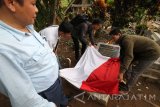 Peziarah membentangkan bendera Merah Putih di atas makam pahlawan nasional Tan Malaka, Desa Selopanggung, Kediri, Jawa Timur, Kamis (9/11). Kegiatan doa bersama oleh sejumlah elemen masyarakat tersebut dalam rangka memperingati Hari Pahlawan. Antara Jatim/Prasetia Fauzani/mas/17.