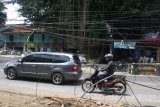 Pengguna jalan berhati-hati saat melintas di samping jaringan kabel sejumlah provider layanan internet yang dibiarkan kusut dan semrawut di Jalan Borobudur, Malang, Jawa Timur, Minggu (12/11). Belum ada penanganan dari pemerintah setempat meski kondisi yang membahayakan bagi pengguna jalan tersebut sudah berlangsung selama hampir dua bulan. Antara Jatim/Ari Bowo Sucipto/uma/17.