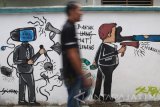 Warga melintas di depan mural bertema 'Generasi Milleneal Anti Hoax' di sebuah gang Kelurahan Banjaran, Kota Kediri, Jawa Timur, Selasa (14/11). Kegiatan dengan membuat lima belas karya mural yang digagas oleh Aliansi Jurnalis Independen (AJI) tersebut bertujuan mengedukasi masyarakat agar berperan serta menangkal arus hoax yang semakin masif dengan tidak ikut serta menyebarkan berita hoax. Antara Jatim/Prasetia Fauzani/mas/17.