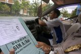 Asisten penguji ujian SIM yang memiliki cacat fisik (tangan)  Subandi (kanan) mengendarai mobil melewati halang rintang buatan di halaman kantor Satpas (Satuan Penyelenggara Administrasi SIM) Polres Trenggalek, Trenggalek, Jawa Timur, Kamis (16/11). Meski hanya menggunakan separuh lengan, Subandi mahir mengendarai kendaraan roda dua maupun roda empat sehingga diperbantukan oleh polisi untuk menjadi asisten petugas penguji dengan menjadi model ujian praktik berkendara bagi pemohon SIM A, B maupun C, baik pemohon dengan fisik normal maupun difabel/berkebutuhan khusus. Antara Jatim/Destyan Sujarwoko/mas/17.