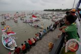 Warga menyaksikan sejumlah perahu yang dihias warna warni berjajar di pinggir pantai saat Parade Kapal Rakyat di Pantai Kenjeran, Surabaya, Jawa Timur, Minggu (19/11). Kegiatan yang diikuti puluhan kapal rakyat dan merupakan rangkaian acara Bulak Fest 2017 tersebut salah satunya bertujuan untuk menarik wisatawan ke tempat wisata pesisir di kawasan utara Surabaya itu. ANTARA FOTO/Didik Suhartono/wdy/2017.