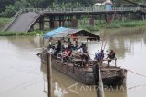 Sejumlah warga memanfaatkan perahu penyeberangan dengan latar belakang jembatan Mrican yang putus di Kelurahan Mrican, Kota Kediri, Jawa Timur, Jumat (24/11). Memasuki musim penghujan, sungai Brantas yang merupakan sungai terpanjang se-Jawa Timur tersebut mengalami peningkatan debit air dan mengacam keselamatan perahu penyeberangan karena derasnya arus. Antara Jatim/Prasetia Fauzani/mas/17.