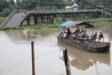 Sejumlah warga memanfaatkan perahu penyeberangan dengan latar belakang jembatan Mrican yang putus di Kelurahan Mrican, Kota Kediri, Jawa Timur, Jumat (24/11). Memasuki musim penghujan, sungai Brantas yang merupakan sungai terpanjang se-Jawa Timur tersebut mengalami peningkatan debit air dan mengacam keselamatan perahu penyeberangan karena derasnya arus. Antara Jatim/Prasetia Fauzani/mas/17.