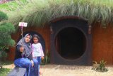 Pengunjung melakukan swafoto di depan wahana rumah hobbit di kawasan wisata Taman Kelinci di Pujon, Malang, Jawa Timur, Kamis (30/11).  Wisata Taman Kelinci  tersebut sengaja dibangun untuk memberi wadah bagi peternak kelinci di sekitar kawasan tersebut sekaligus menarik wisatawan untuk datang berkunjung. Antara Jatim/Ari Bowo Sucipto/mas/17.