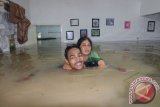 Seorang warga mengevakuasi tetangganya yang terjebak banjir di rumahnya, kawasan pinggiran Sungai Deli, Kecamatan Medan Maimun, Medan, Sumatera Utara, Selasa (7/11). ANTARASUMUT/Irsan Mulyadi/17.