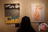 Seorang pengunjung mengamati dua kartun berjudul 'Hoax di Medsos' (kiri) karya Apat dan 'Jerapah' (kanan) karya Ambar Pratiwi, pada Pameran Kartun Akhir Tahun 2017, di Galeri Cipta 3, TIM, Jakarta, Senin (11/12). Pameran yang diselenggarakan Persatuan Kartunis Indonesia (PAKARTI) ini dijadwalkan berlangsung hingga 18 Desember 2017. ANTARA FOTO/Dodo Karundeng/wdy/2017.