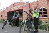 Dua orang polisi bersiap melakukan patroli dengan sepeda di depan pos pengamanan Natal berbentuk Rumah Salju di area Alun-alun Kota Kediri, Jawa Timur, Minggu (24/12). Polisi membangun pos pengamanan di sejumlah titik keramaian dan rutin melakukan patroli dengan sepeda guna memberikan rasa aman warga dalam beribadah ataupun beraktivitas mengisi liburan. Antara Jatim/Prasetia Fauzani/mas/17.