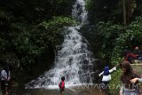 Sejumlah wisatawan menikmati pemandangan alam di area air terjun Irenggol, Kediri, Jawa Timur, Kamis (28/12). Air terjun setinggi 80 meter di lereng gunung Wilis tesebut menjadi salah satu destinasi wisata yang ramai dikunjungi wisatawan pada musim libur panjang sekolah. Antara Jatim/Prasetia Fauzani/mas/17.