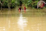 Warga berjalan melintasi banjir di Desa Meuria Matangkuli, Kabupaten Aceh Utara, Aceh, Rabu (3/1). Banjir yang disebabkan meluapnya sungai Krueng Keureuto dan Sungai Pirak itu menyebabkan ribuan rumah di empat kecamatan di Aceh Utara terendam sehingga warga terpaksa mengungsi. ANTARA FOTO/Rahmad/pras/17.