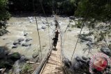 Polisi melintasi jembatan gantung yang ambruk di Tanjung Sari, Bogor, Jabar Selasa (2/1). Jembatan gantung yang menjadi akses penyeberangan wisata penangkaran rusa itu ambruk pada Senin (1/1) diduga karena kelebihan beban, mengakibatkan 30 korban luka seorang meninggal dunia. (ANTARAFOTO/Yulius Satria Wijaya)