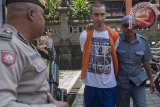 Polisi dan petugas Kejaksaan Negeri Denpasar menggiring tahanan warga Amerika Serikat, Christian Beasley (tengah) yang sempat melarikan diri dari Lembaga Pemasyarakatan (Lapas) Kerobokan, menjelang mengikuti sidang di Pengadilan Negeri Denpasar, Kamis (4/1). Warga Amerika Serikat yang ditahan karena membawa 5.7 gram hashish tersebut kembali mengikuti proses persidangan di pengadilan setelah berhasil ditangkap dalam pelariannya di Lombok pada 15 Desember 2017. Antara Bali/Nyoman Budhiana/nym/2018.