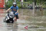 Wisatawan mancanegara mendorong motor saat banjir di kawasan Jalan Dewi Sri, Kuta, Badung, Bali, Selasa (23/1). Hujan dengan intensitas tinggi yang mengguyur kawasan Badung sejak Senin (22/1) tersebut mengakibatkan banjir di berbagai titik di sejumlah kawasan Kuta, Legian dan Seminyak dengan ketinggian yang bervariasi. ANTARA FOTO/Fikri Yusuf/wdy/2018