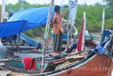 Nelayan membenahi perahu yang ditambatkan di Pantai Pegagan, Pamekasan, Jawa Timur, Jumat (5/1). Kementerian Kelautan dan Perikanan (DKP) akan memberikan bantuan kapal kepada nelayan sebanyak 513 unit, 1.000 unit  mesin kapal berukuran di bawah 10 gross tonnage (GT) serta 1.702 paket alat tangkap ikan guna memenuhi target produksi perikanan tangkap dari 7,8 juta ton pada 2017 menjadi 9,45 juta ton pada tahun 2018. Antara Jatim/Saiful Bahri/mas/18.