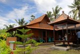 Wisatawan menikmati suasana di griya ekologi rumah adat suku osing di Kelir, Banyuwangi, Jawa Timur, Jumat (19/1). Rumah ekologi itu, dibangun untuk sarana edukasi mengenal lingkungan dan budaya seperti rumah adat suku osing yang tahan guncangan gempa. Antara Jatim/Budi Candra Setya/zk/18. 