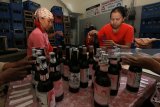 Pekerja memasang label pada botol berisi kecap di pabrik Kecap Manis Cap Jeruk Pecel Tulen di Surabaya, Jawa Timur, Jumat (26/1). Produksi kecap berbahan baku kedelai hitam yang didatangkan dari Pati maupun Jember di pabrik yang berdiri sejak tahun 1937 itu mencapai sekitar 2.400 botol per hari dengan harga jual Rp18.000 per botol per 600 ml. Antara Jatim/Didik Suhartono/zk/18 