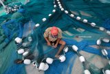 Nelayan memperbaiki jaring di Pelabuhan Ikan Muncar, Banyuwangi, Jawa Timur, Kamis (18/1). Sebagian besar nelayan yang menggunakan jaring tradisional di daerah tersebut, mengaku kecewa atas dicabutnya larangan penggunaan jaring cantrang yang dianggap akan merusak ekosistem bawah laut dan berdampak pada pendapatan nelayan tradisional. Antara Jatim/Budi Candra Setya/zk/18.