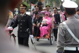 Pensiunan polisi beserta istri menaiki becak yang dikemudikan oleh Kapolresta Kediri AKBP Anthon Haryadi (tengah) melintas di salah satu jalan protokol Kota Kediri, Jawa Timur,Jumat (26/1). Pawai dengan menggunakan becak hias tersebut sebagai simbolisasi penghargaan dan ucapan terima kasih keluarga besar polres Kediri kepada anggota yang telah memasuki purna tugas. Antara jatim/Prasetia Fauzani/zk/18