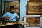 Perajin disabilitas Jamaludin menyelesaikan lukisannya yang berbahan dasar dari pelepah pisang di rumahnya kawasan Kenjeran, Surabaya, Jawa Timur, Selasa (16/1). Kerajinan pelepah pisang itu telah dipasarkan di berbagai daerah di Indonesia bahkan hingga Amerika, Belanda, Malaysia, dan Singapura, dengan harga Rp100 ribu hingga Rp5 juta tergantung dari bentuk dan ukuran. Antara Jatim/M Risyal Hidayat/zk/18