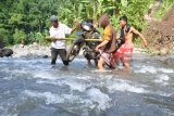 Warga bergotong royong mengangkut sepeda motor saat menyeberangi sungai di Desa Campoan, Mlandingan, Situbondo, Jawa Timur, Selasa (30/1). Sebanyak 70 kepala keluarga di desa tersebut terisolasi, karena jembatan penghubung rusak diterjang banjir dan belum diperbaiki selama setahun terakhir.  Antara Jatim/Seno/zk/18.
