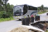 Sebuah bus antar negara jurusan Pontianak-Kuching (Malaysia) melintasi jalan darat lintas negara yang kondisinya amblas sejak sepekan lalu di Kecamatan Sekayam, Kabupaten Sanggau, Kamis (25/1). Amblasnya bahu jalan yang disebabkan oleh tingginya curah hujan sejak awal 2018 tersebut, dikhawatirkan dapat memutuskan jalur darat lintas negara menuju Pos Lintas Batas Negara (PLBN) Entikong, Kabupaten Sanggau. ANTARA FOTO/Agus Alfian/jhw/18