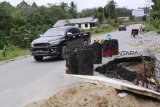 Sebuah mobil Malaysia melintasi jalan darat lintas negara yang kondisinya amblas sejak sepekan lalu di Kecamatan Sekayam, Kabupaten Sanggau, Kamis (25/1). Amblasnya bahu jalan yang disebabkan oleh tingginya curah hujan sejak awal 2018 tersebut, dikhawatirkan dapat memutuskan jalur darat lintas negara menuju Pos Lintas Batas Negara (PLBN) Entikong, Kabupaten Sanggau. ANTARA FOTO/Agus Alfian/jhw/18