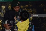 Prajurit TNI Batalyon Infanteri Para Raider 501/Bajra Yudha yang tergabung dalam Satgas Pengamanan Perbatasan (Pamtas) RI-Papua Nugini memeluk anak dan isterinya sesaat sebelum berangkat di markasnya Madiun, Jawa Timur, Jumat (9/2). Sebanyak 450 prajurit Para Raider 501/Bajra Yudha diberangkatkan untuk bertugas mengamankan wilayah perbatasan RI-Papua selama sembilan bulan. Antara Jatim/Foto/Siswowidodo/zk/18