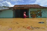 Warga membersihkan sampah didepan rumahnya sambil menunggu surutnya air banjir di Desa Tanjungsari, Kabupaten Tasikmalaya, Jawa Barat, Jumat (23/2). Banjir setinggi 50 cm sampai satu meter yang terjadi tadi malam akibat meluapnya sungai Cikidang ditambah intensitas curah hujan yang tinggi. ANTARA JABAR/Adeng Bustomi/agr/18 