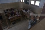 Guru mengajari siswa di satu ruang yang disekat dengan dinding pemisah darurat untuk dua kelas berbeda di SDN 04 Kedoyo, Tulungagung, Jawa Timur, Kamis (8/2). Pihak sekolah terpaksa membagi ruang di tiga lokal yang tersisa untuk siswa kelas 1-6, karena satu lokal bangunan untuk kelas 1 dan 2 mengalami kerusakan berat. Antara Jatim/Destyan Sujarwoko/zk/18