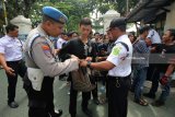 Polisi dan petugas keamanan memeriksa tas milik anggota Persaudaraan Setia Hati Terate (PSHT) saat berlangsungnya sidang dengan terdakwa Jhonerly Simanjuntak, di Pengadilan Negeri Surabaya, Jawa Timur, Kamis (22/2). Sekitar 750 personel baik dari kepolisian maupun TNI disiagakan untuk mengamankan jalannya sidang yang juga didatangi ratusan massa pendukung baik dari Bonek dan Persaudaraan Setia Hati Terate (PSHT) itu. Antara Jatim/Didik Suhartono/zk/18