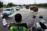 Polisi mengatur arus lalu lintas kendaraan yang melintasi genangan banjir di Jalan Raya Porong, Sidoarjo, Jawa Timur, Jumat (16/2). Banjir yang melanda Jalan raya Porong setinggi 70 cm selama beberapa hari terakhir menyebabkan terganggunya aktivitas transportasi. Antara jatim/Umarul Faruq/zk/18