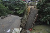 Warga berada disekitar jembatan Cikaroya yang putus di desa Gumulung Lebak, Beber, Cirebon, Jawa Barat, Minggu (25/2). Jembatan penghubung dua kecamatan yaitu kecamatan Beber dan Greged tersebut putus akibat terjangan air saat banjir terjadi pada hari sabtu (24/2) lalu. ANTARA JABAR/Dedhez Anggara/agr/18.