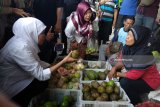 Calon Gubernur Khofifah Indar Parawansa (tengah) membeli dagangan penjual saat kampanye tatap muka dengan pedagang dan warga di Pasar Ngemplak, Tulungagung, Jawa Timur, Minggu (25/2). Selama di Tulungagung Khofifah memilih kampanye dengan blusukan ke pasar-pasar tradisional dan kawasan pesisir selatan untuk bertatap muka langsung dengan masyarakat dan menyosialisasikan program-programnya. Antara Jatim/Destyan Sujarwoko/zk/18